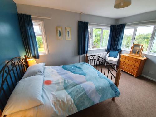 a bedroom with a bed and a chair and windows at Ty Pren Bach in Maenclochog