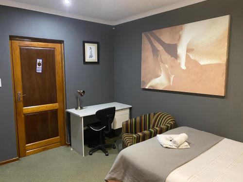 a bedroom with a bed and a desk and a chair at Marion Lodge in Johannesburg