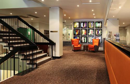 a hallway with stairs and orange chairs in a building at Winchester Wessex Hotel by Sunday in Winchester