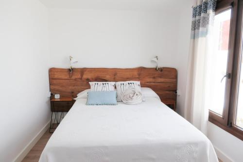um quarto com uma cama branca e uma cabeceira em madeira em Casa Viges em El Pinar del Hierro