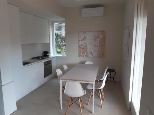 een witte keuken met een tafel en witte stoelen bij Olivo House 2 in Portovenere