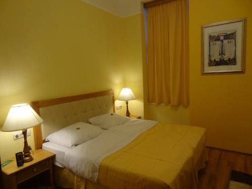 ein Schlafzimmer mit einem Bett, zwei Lampen und einem Fenster in der Unterkunft Residence Parliament in Budapest