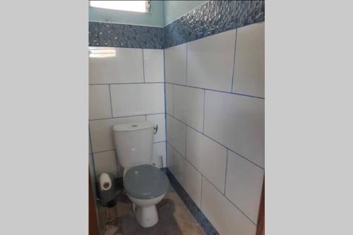 a bathroom with a toilet and white tiled walls at La Kaz d'Évania in Sainte-Rose
