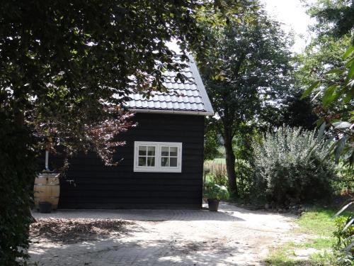 a black house with a white window and trees at The Green Cottage in Ruinen