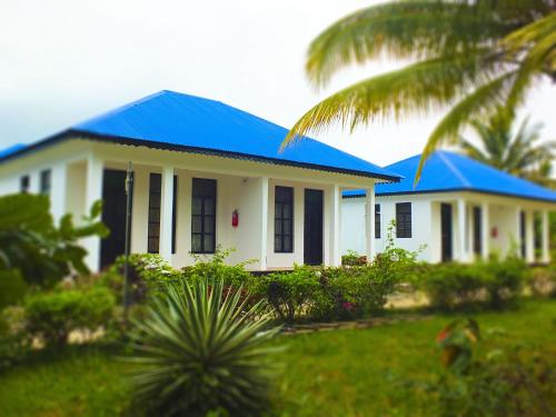a white house with a blue roof at Kigwedeni Villas in Nungwi