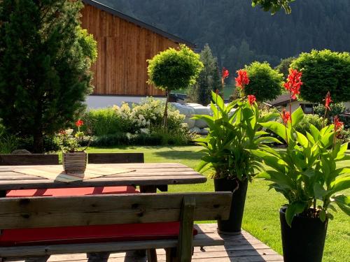 a picnic table and bench in a garden with flowers at Ferienwohnungen Monika Winter in Kleinarl