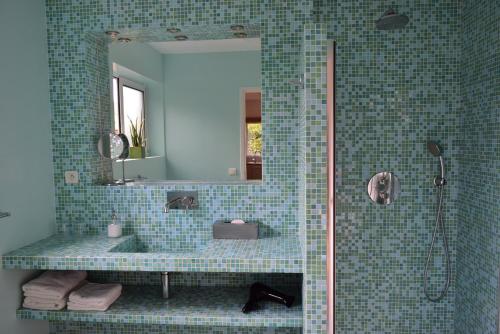 a blue tiled bathroom with a shower and a mirror at Fare Bambou in Gujan-Mestras