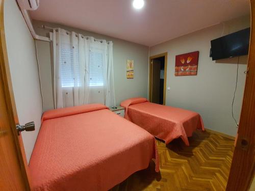 Habitación con 2 camas con sábanas de color naranja en El Gaitero 2, en Arroyomolinos