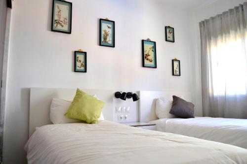 twee bedden in een kamer met foto's aan de muur bij El Encanto in Fuengirola