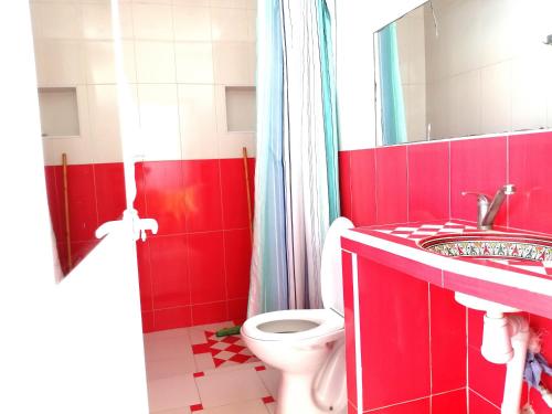 La salle de bains rouge est pourvue de toilettes et d'un lavabo. dans l'établissement chez souad, à Oualidia