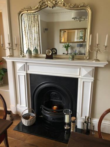 a fireplace in a living room with a mirror at Ballifeary House in Inverness