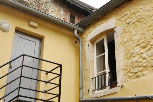 un edificio amarillo con puerta y balcón en Les Oiseaux de Passage, en Saint-Gaultier