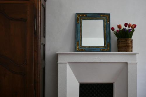 a mirror sitting on top of a fireplace with tulips at Les Oiseaux de Passage in Saint-Gaultier