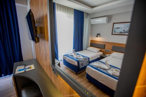 a hotel room with two beds and a tv at Kleopatra Fatih Hotel in Alanya