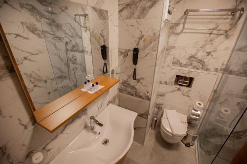 een badkamer met een wastafel, een toilet en een spiegel bij Kleopatra Fatih Hotel in Alanya