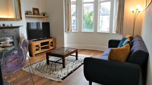 a living room with a couch and a tv at Beautifully renovated 2 Bed flat - Close to beach in Southend-on-Sea