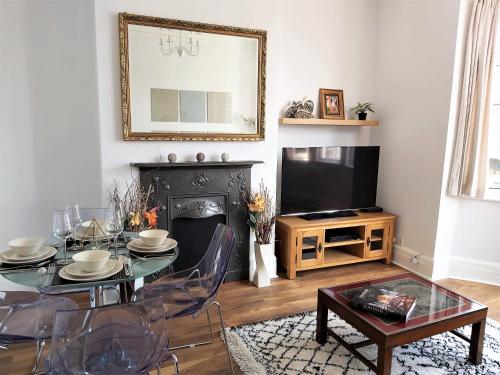 ein Wohnzimmer mit einem Tisch und einem TV in der Unterkunft Beautifully renovated 2 Bed flat - Close to beach in Southend-on-Sea