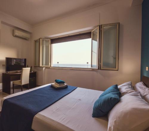 um quarto com uma cama grande e uma janela em Oasis em Acitrezza