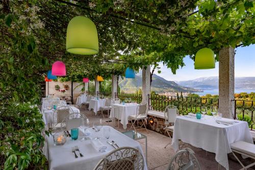 a restaurant with white tables and chairs and vines at Villa Arcadio Hotel & Resort in Salò
