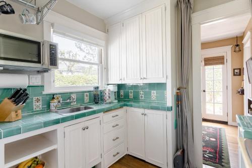 a kitchen with white cabinets and green tiles at Casita Charm, Cozy Character in Long Beach