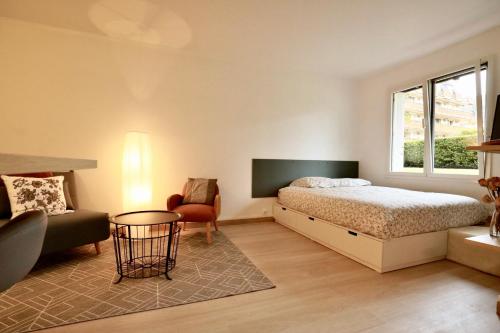 a bedroom with a bed and a chair and a window at Studio Royal de la Plage in Deauville