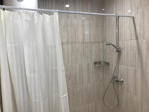 a shower with a white shower curtain in a bathroom at Студио Сънрайз А28, Лозенец in Lozenets