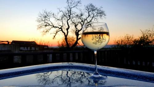 una copa de vino sentada en una mesa con la puesta de sol en The Orange Fox Lux Room and Hot Tub at The Grumpy Schnauzer Guest House en Airdrie