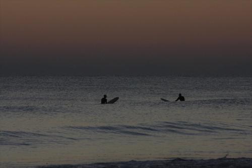 two people sitting on surfboards in the ocean at Aqua Boutique Hotel in Castiglione della Pescaia