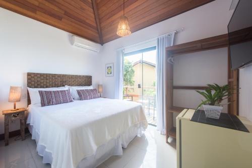 a bedroom with a white bed and a large window at GUAPAS BUZIOS Exceptional House - Ferradurinha in Búzios
