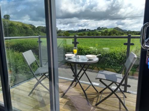 una mesa y sillas en un balcón con vistas en Gerycastell Luxury Holiday Apartment with Stunning Views & EV Station Point en Carmarthen