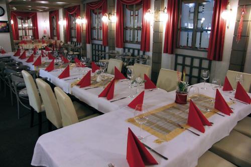 una habitación con mesas largas con servilletas rojas. en Hotel am Schloss Neuenstein en Neuenstein