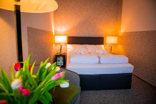 a hotel room with a bed with two lamps and flowers at Bölsche Hotel in Berlin