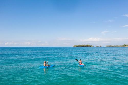 two people in a body of water with a surfboard at Palmar Beach Lodge in Bocas Town