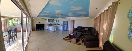 a living room with a couch and a ceiling with clouds at Illovo Beach house in Amanzimtoti