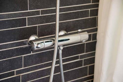 a shower head in a bathroom with a brick wall at Cozy summer house 50 meter from the beach, 89 m² in Dronningmølle