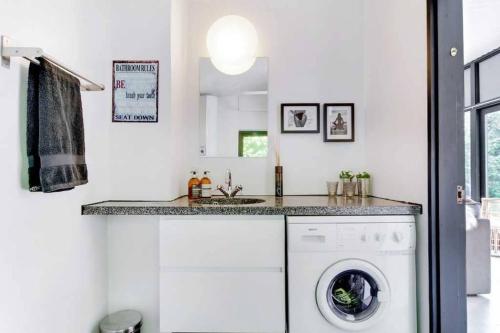 a white laundry room with a washer and dryer at Cozy summer house 50 meter from the beach, 89 m² in Dronningmølle