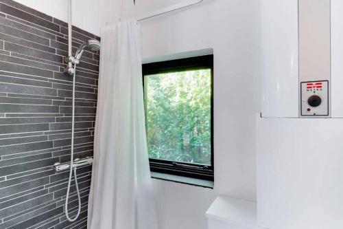 een badkamer met een douchegordijn en een raam bij Cozy summer house 50 meter from the beach, 89 m² in Dronningmølle