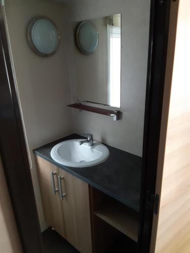 W łazience znajduje się umywalka i lustro. w obiekcie Mobil-home Confort camping le bois Masson w mieście Saint-Jean-de-Monts