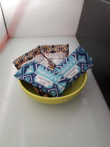 a yellow bowl filled with packets of candy on a table at LOFT NOVO CONFORTÁVEL in Sorocaba