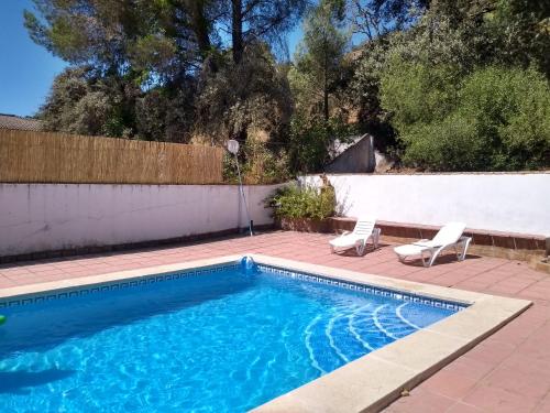 a swimming pool with two chairs and a fence at La Caballera 17 in Santa María de Trassierra