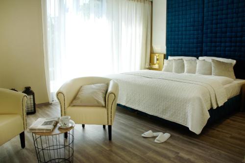 sypialnia z dużym białym łóżkiem i krzesłem w obiekcie Hotel Athen Kelsterbach Frankfurt Airport w mieście Kelsterbach