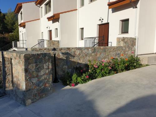 a stone retaining wall next to a building with flowers at Melissonas Villas in Phini