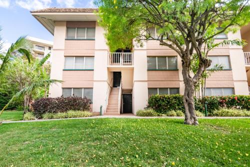 a building with a tree in front of a yard at Amazing Kihei Kai Nani - Maui Vista One Bedroom Condos in Kihei