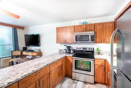 a kitchen with wooden cabinets and stainless steel appliances at Amazing Kihei Kai Nani - Maui Vista One Bedroom Condos in Kihei