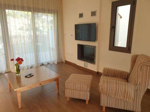 a living room with a table and a chair and a tv at Melissonas Villas in Phini