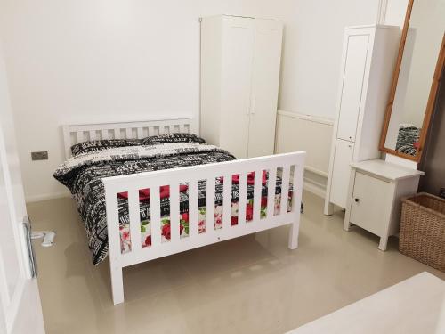 Una cuna blanca en un dormitorio con cama en Observation Court en Ipswich