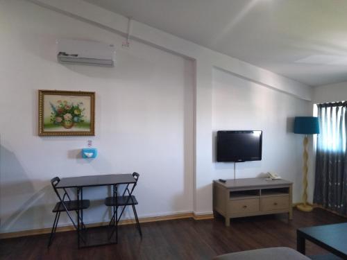 Ginasuite Kompleks27 Hotel في بندر سيري بيغاوان: غرفة معيشة مع طاولة وتلفزيون على الحائط