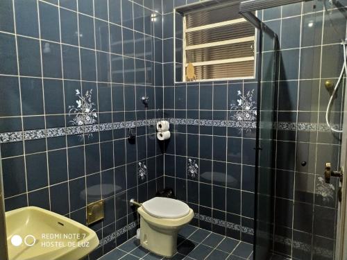 y baño de azulejos azules con aseo y bañera. en Hostel de Luz - Unidade 1 en Campinas