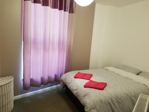 a bedroom with a bed with two red pillows on it at Alhambra Suite in Ipswich