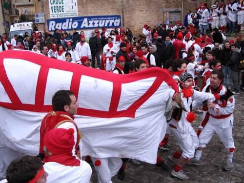 a group of people dressed in red and white carrying a flag at La Neviera Nel Pozzo in Offida